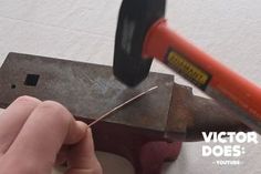 a person is using a hammer to cut metal with a small piece of pliers