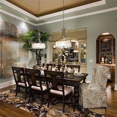 a dining room table with chairs and a chandelier hanging from the ceiling in front of a painting