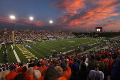 a football stadium filled with people watching a game at sunset or dawn in the evening