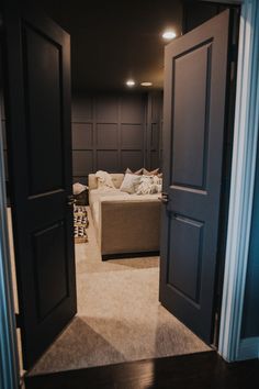 an open door leading to a living room with a couch in the corner and pillows on the floor