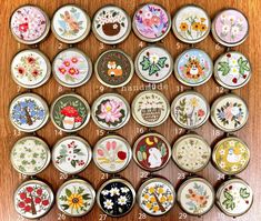 many different types of flowers and birds in small tins on a wooden table top