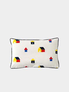 a white pillow with colorful houses on the front and back, along with black piping