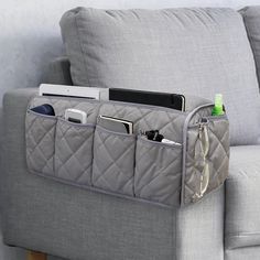 a gray couch with a laptop and cell phone in it's pocket on the arm