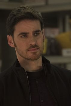 a man in a black jacket looking at the camera with a serious look on his face