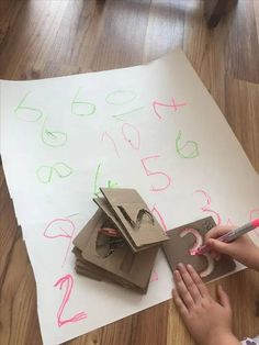 a child is drawing numbers on paper with crayons