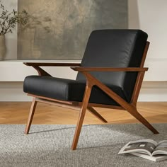 a black leather chair sitting on top of a wooden floor next to an open book