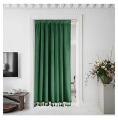 a green curtain with tassels hangs in front of a white wall and floor