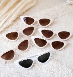 six pairs of white sunglasses with pearls on the rims and one pair is black