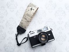 an old camera and umbrella laying on a wallpapered floor with damask paper