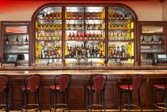 a bar with red chairs and lots of bottles