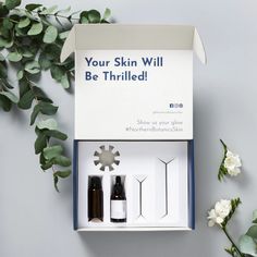 an open box containing three bottles of skin care products, with flowers in the background