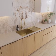 a kitchen with marble counter tops and wooden cabinets, gold faucet in the center