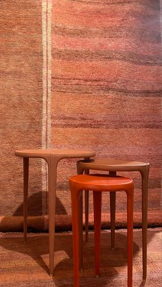 two tables sitting next to each other in front of a wall with an area rug