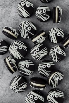 black and white decorated cookies with eyes on them sitting on a gray surface next to each other