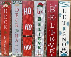 christmas signs are lined up on the side of a brick wall in front of a building