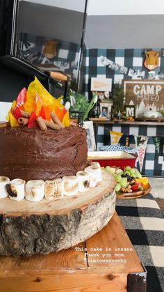 a chocolate cake with marshmallows and fruit on top sitting on a table