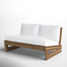 a wooden couch with white pillows on it's back and side ends, in front of a plain background