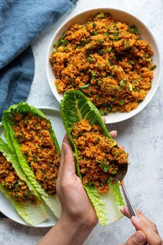 two plates filled with lettuce and meat on top of each other next to a person holding a fork