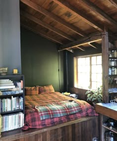 a bed sitting under a window next to a book shelf filled with lots of books