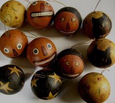 six wooden balls with painted faces and stars hanging from strings on a white table top