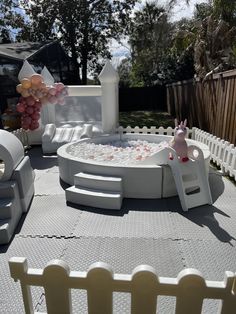 an inflatable hot tub surrounded by white chairs and tables with balloons on them