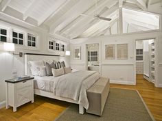 a bedroom with white walls and wood flooring has a large bed in the center