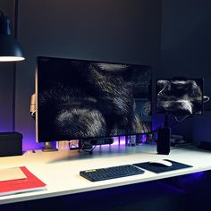 two computer monitors sitting on top of a white desk next to a keyboard and mouse