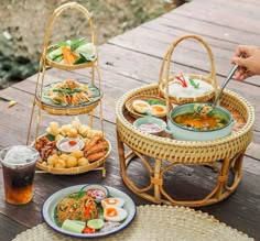 three baskets with food on them sitting on a wooden table next to drinks and plates