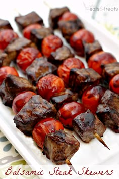 the skewers are covered with kebabs and cherry tomatoes on a white plate