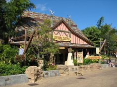 the entrance to an amusement park with people sitting on benches in front of it and trees around