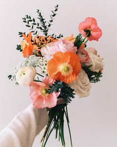 a person holding a bouquet of flowers in their hand with white gloves on the arm