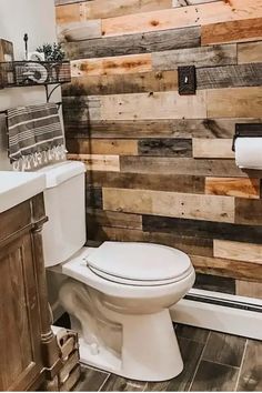 Modern bathroom with wooden accent wall and rustic decor, including a white toilet and mounted toilet paper holder. Pallet Wall Ideas, Flooring On Walls, Diy Wooden Wall, Palette Wall, Wood Wall Bathroom, Wood Plank Walls