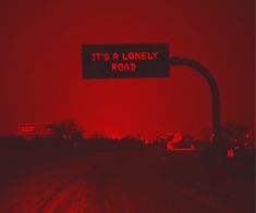 a red street sign that says it's a lonely road