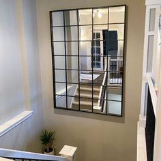 a mirror on the wall above a toilet in a room with white walls and stairs