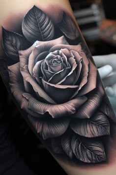 a black and white rose tattoo on the right arm, with leaves around it's edges