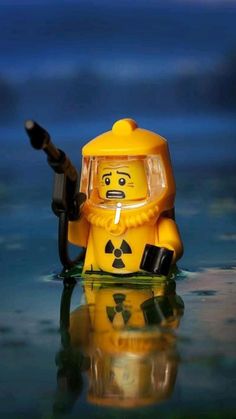 a yellow toy with a radioactive face holding a black object in it's hand