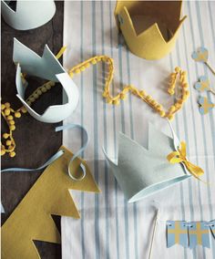 some paper crowns are on a table with other items around them and one is yellow