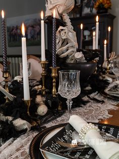 the table is set with candles, plates and napkins for halloween dinnerware decor