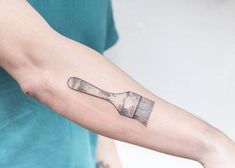 a person with a tattoo on their arm holding a brush