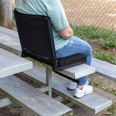 a woman sitting on top of a wooden bench