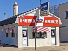 a small white building with red and white awnings on the front, next to a motorcycle parked outside