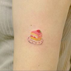 a small piece of cake tattoo on the right side of the thigh, with a strawberry on top