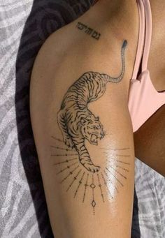 a woman's arm with a tiger tattoo on it and an arrow in the middle