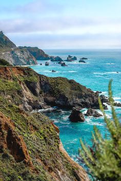 the ocean is blue and green with waves coming in from the rocks on the shore