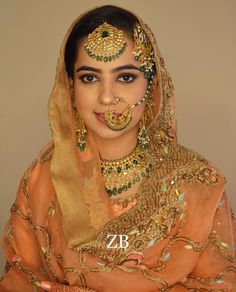 a woman in an orange outfit with gold jewelry on her face and nose is posing for the camera