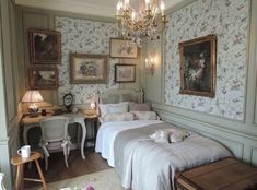 a bed room with a neatly made bed and a chandelier hanging from the ceiling