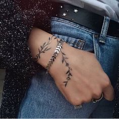 a woman's hand with a tattoo on it, holding onto her jeans and wearing a black cardigan