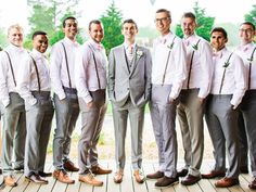 a group of men standing next to each other on top of a wooden floor in front of trees