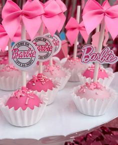 pink and white cupcakes with bows are on a cake platter at a barbie birthday party