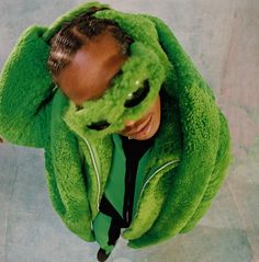 a man wearing a green jacket and covering his eyes with a mask on top of his head